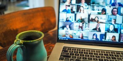 Laptop with video call and coffee mug.