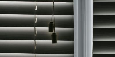 Close-up of dark window blinds with pull cords.